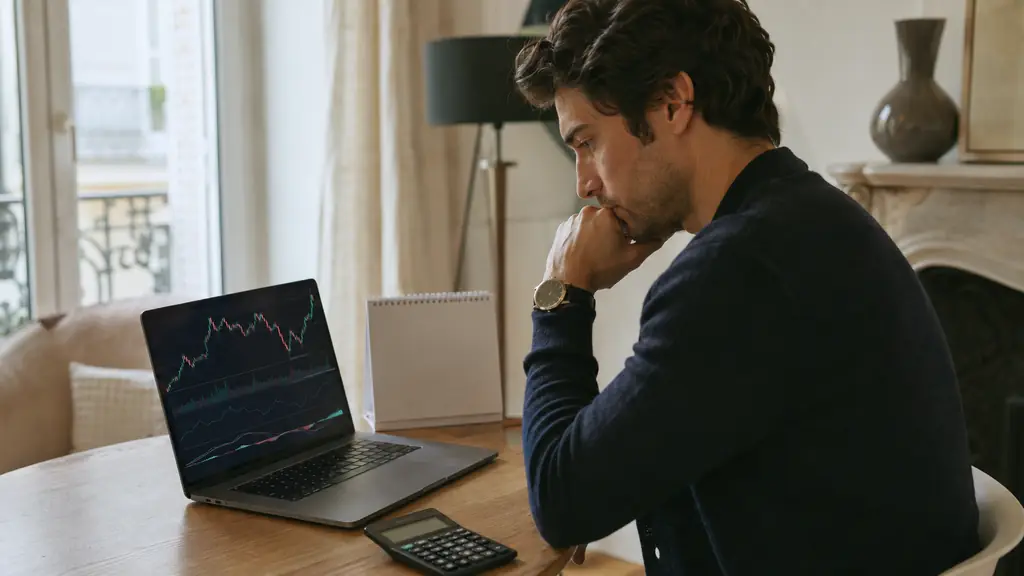focused trader comparing a demo trading chart on a laptop with a desk calendar and calculator beside it, editorial photography, no visible text or logos
