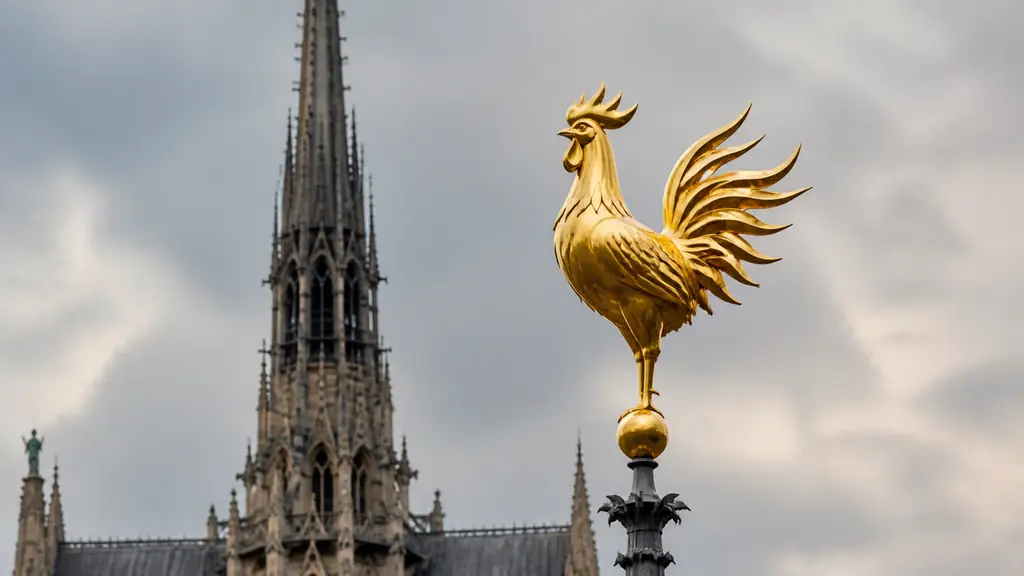 Editorial close-up photograph of the new golden rooster of Notre-Dame, showing its flame-shaped wings and sculpted metal silhouette atop the reconstructed spire, no text, no logo