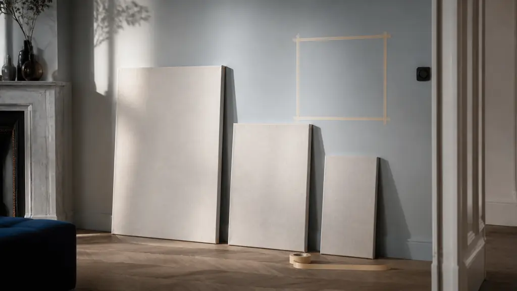editorial photograph of three blank stretched canvases in different widths leaning against a wall, with a measuring tape and masking-tape square outline, soft natural light, no text, no logo