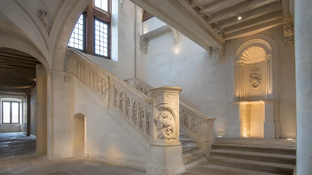 Interior architectural photograph of the restored southern wing of the Château de Villers-Cotterêts, featuring a carved salamander emblem, fleurs-de-lis ornaments and a Renaissance stone staircase, no text or logo