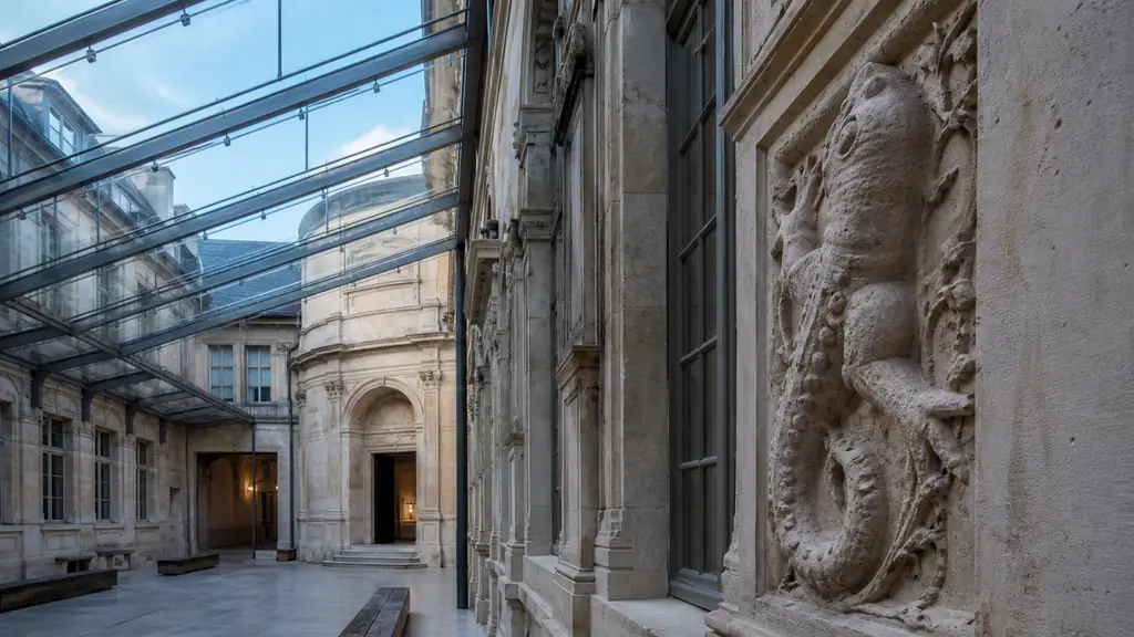 Glass canopy above the Jeu de paume courtyard with a Renaissance salamander carving and the entrance to the royal chapel, no visible lettering or logos