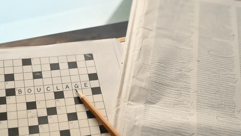 close-up photograph of a crossword grid filled with BOUCLAGE, a pencil pointing to crossed letters, and a proofread newspaper page on a desk, no text overlay or logo